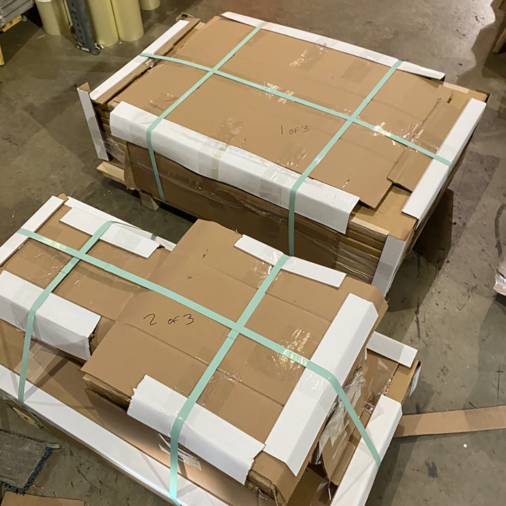 Two large LTL freight pallets stacked with hundreds of individually boxed traffic signs secured with green banding straps on the Rice Signs warehouse shipping floor, labeled 1 of 3 and 2 of 3 in handwritten marker