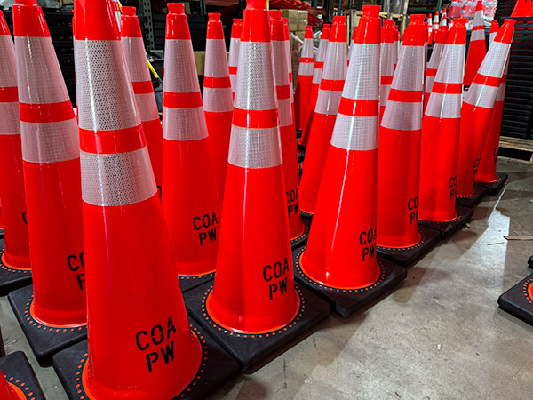 Several dozen reflective traffic cones with the name of the customer stenciled on the bottom.