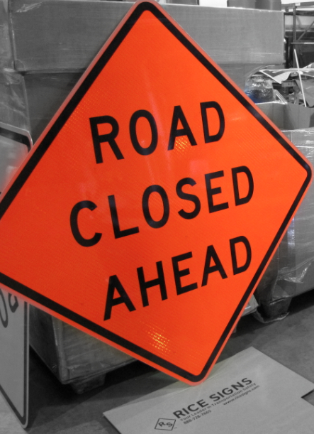 Fluorescent orange Road Closed Ahead sign shown